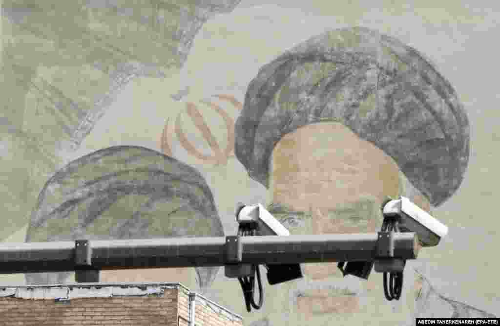 Тегерандын көчөсүндөгү аятолла Рухолла Хомейнинин сүрөтүнүн алдына илинген видео камера. IRNA агенттиги 9-апрелде иран полициясы коомдук жайларда хижаб кийбеген аялдарды көзөмөлдөө жана аныктоо үчүн көчөлөргө заманбап видео камералар орнотуларын жарыялаган.&nbsp;Былтыр сентябрда Иранда 22 жаштагы студент кыз Махса Амини полиция хижаб эрежесин бузган деп кармап кеткенден кийин каза тапкан. Анын өлүмүнөн кийин Иранда бир нече айга созулган жапырт толкундоолор болгон. (EPA-EFE/ABEDIN TAHERKENAREH)