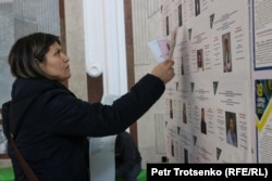Женщина изучает списки кандидатов в депутаты во время парламентских выборов. Алматы, 19 марта 2023 года