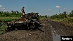 Украинский военный осматривает разбитый российский танк в Новодаровке, Запорожская область