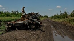 Украинский военный осматривает разбитый российский танк в Новодаровке, Запорожская область