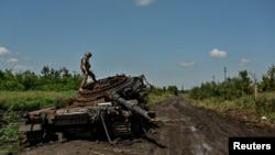 Український військовослужбовець оглядає підбитий російський танк у Новодарівці, фото ілюстративне 