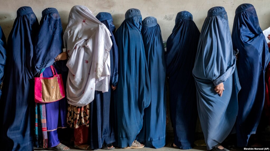 Afghan women wait to receive food rations distributed by a humanitarian aid group in Kabul.