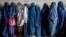 Afghan women wait to receive food rations distributed by a humanitarian aid group in Kabul.