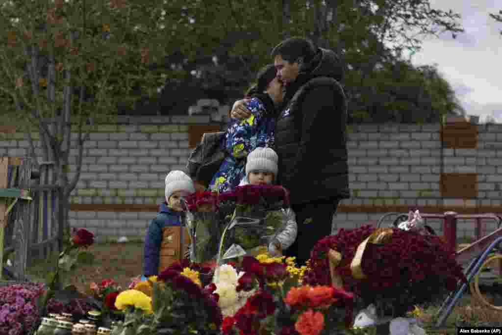 People react near a memorial for the victims of a deadly Russian rocket attack in the Ukrainian village of Hroza near Kharkiv.