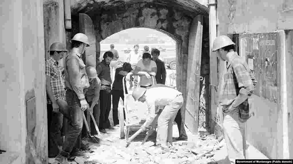 Workers clear the rubble from a lane following the earthquake. Today, no discernible damage is evident. &nbsp;