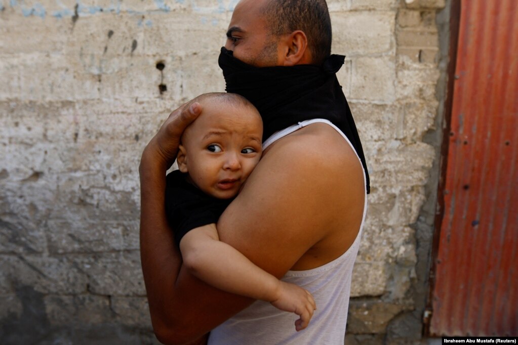 Një burrë duke mbajtur në krahë një fëmijë të vogël pas sulmeve izraelite, në Khan Younis në Rripin jugor të Gazës, 14 tetor 2023.