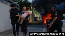 Police help evacuate a woman with a small child from the site of a rocket attack in Ashkelon, Israel, on October 7.