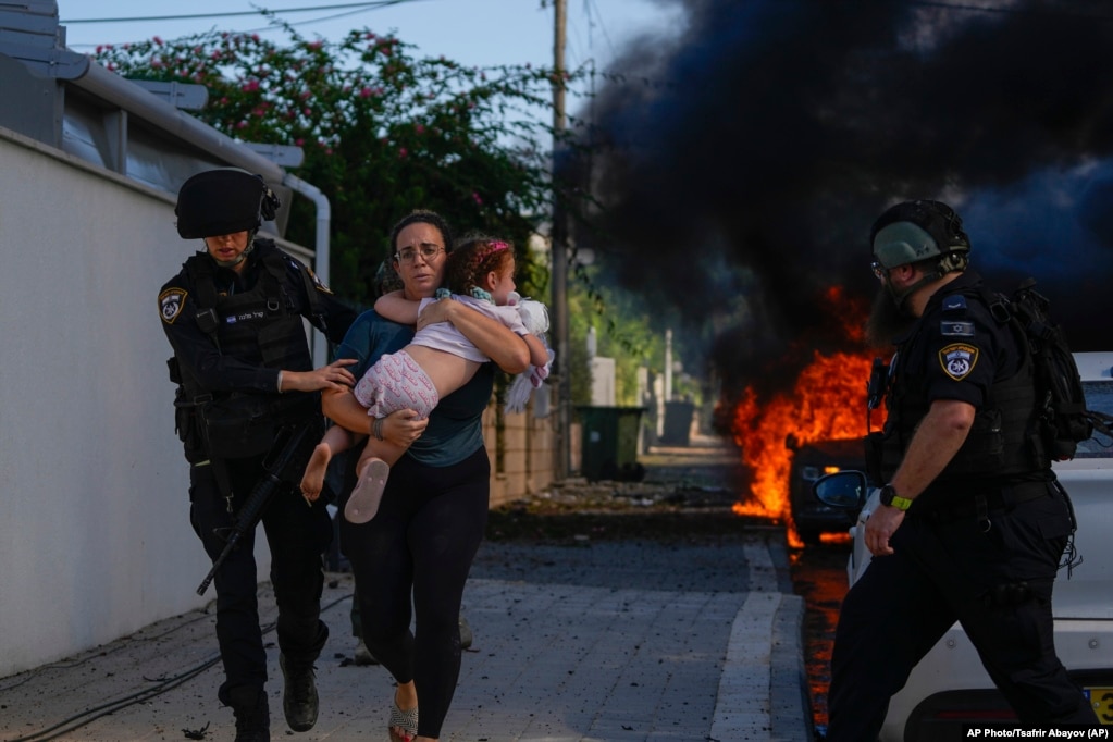 Zyrtarët policorë evakuojnë një grua me vajzën e saj, pasi një raketë godet Ashkelonin. 