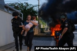 Поліція допомагає евакуюватися жінці з дитиною з місця ракетного удару в Ашкелоні, Ізраїль, 7 жовтня 2023 року