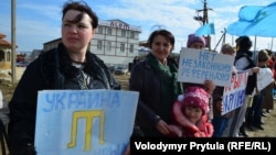 Кримчани з дітьми тримають кримськотатарську символіку та плакати проти проведення псевдореферендуму в Криму, призначеного на 16 березня 2014 року. Околиці Сімферополя, Крим, 14 березня 2014 року