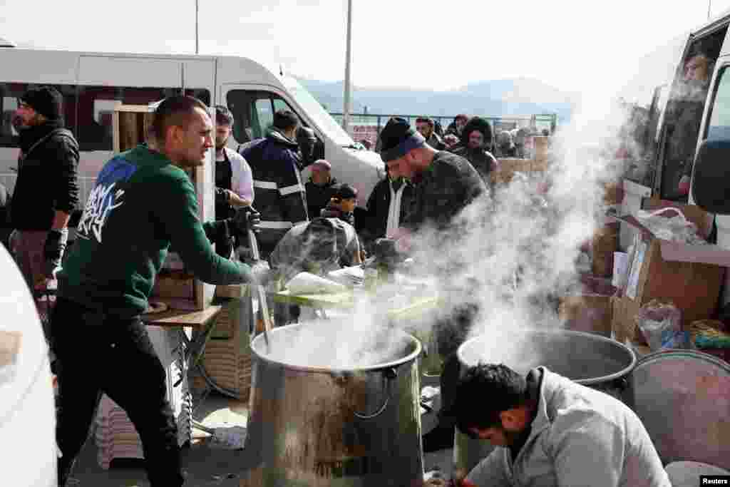 Vullnetarët duke zier çorba në ambient të hapur për personat e zhvendosur brenda në kamp në stadiumin e qytetit Hatay, Turqi.