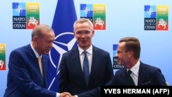 Турският президент Реджеп Таийп Ердоган и шведският премиер Улф Кристершон си подават ръце пред генералният секретар на НАТО Йенс Столтенберг.