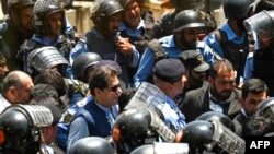 Policemen escort former Pakistani Prime Minister Imran Khan (center) as he arrives at the high court in Islamabad on May 12.