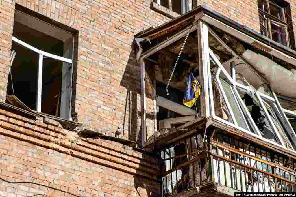 Український прапор на балконі квартири, яка зазнала руйнування внаслідок російського ракетного обстрілу в Шевченківському районі Києва, жовтень 2022 року&nbsp;