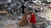 Një grua dhe një vajzë e vogël duke ecur nëpër rrënoja, pas sulmeve ajrore izraelite në kampin e refugjatëve Nuseirat në Rripin e Gazës më 9 qershor 2024. 