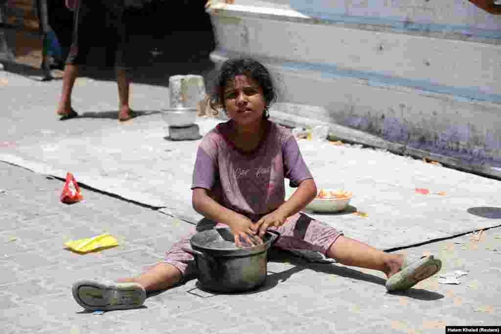 Një vajzë ulet në tokë ndërsa palestinezët mblidhen për të marrë ushqim të gatuar nga një kuzhinë bamirësie, mes mungesës së furnizimeve me ndihma në Han Junis, 19 qershor 2024.