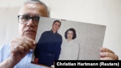 Taghi Ramahi, the husband of jailed Nobel laureate Narges Mohammadi, poses with an undated photo of himself and his wife. (file photo)