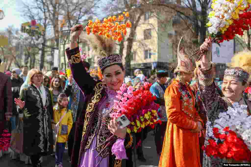 Женщина позирует фотографу во время праздничного шествия по центру Алматы