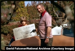 An American father and son warn off potential gasoline thieves in April 1974.