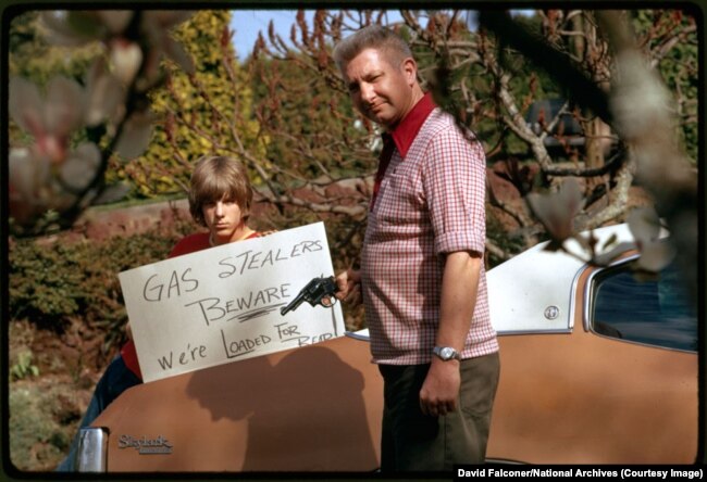 Një baba amerikan me të birin paralajmërojnë hajdutët e mundshëm të benzinës, prill 1974.