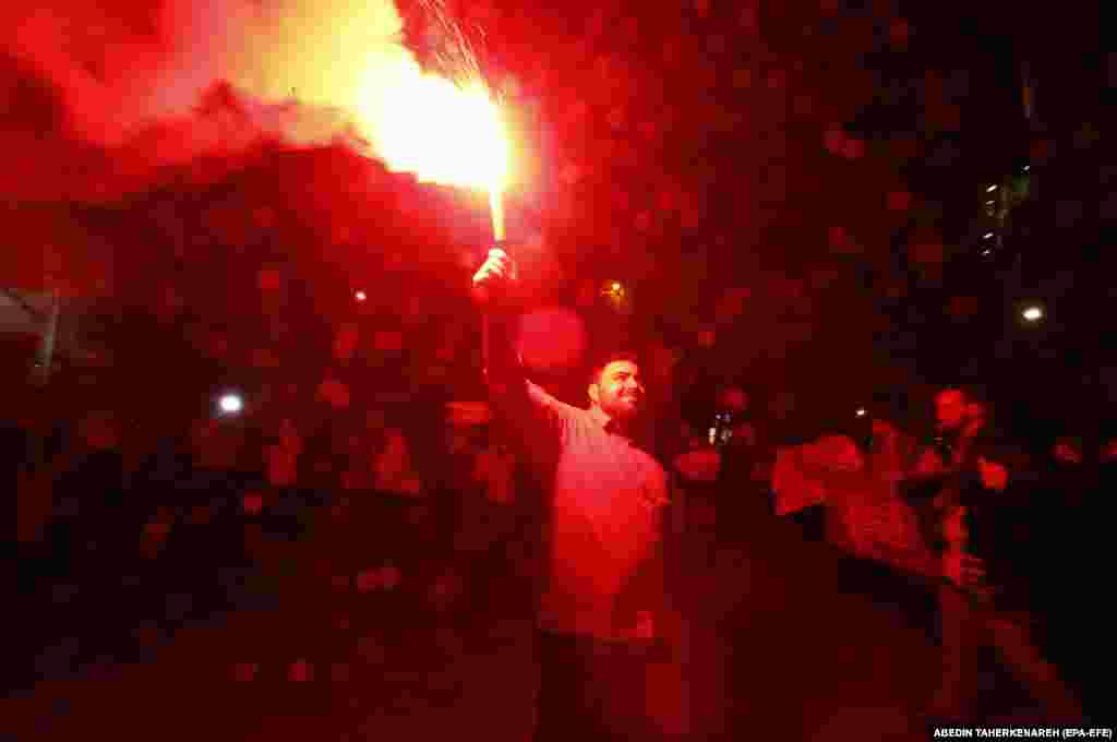 An Iranian man celebrates with a lit flare in Tehran. The attack is the first-ever direct attack on Israeli territory, risking a major escalation as the United States pledged &quot;ironclad&quot; backing for Israel.
