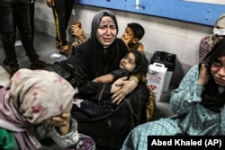 Wounded Palestinians sit in the Al-Shifa hospital in Gaza City after arriving from the Al-Ahli hospital following an explosion there on October 17.