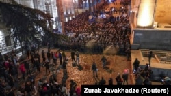 Полицейские вытесняют протестующих с улицы, ведущей к заднему входу в здание парламента Грузии (на фото справа)