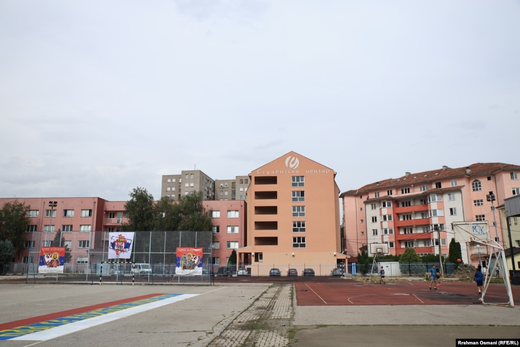 Fëmijët luajnë në një fushë basketbolli pranë një grafiti ku shkruan “Kur ushtria të kthehet në Kosovë”, në Mitrovicën e Veriut.