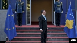 Kryeministri në detyrë i Kosovës, Albin Kurti, duke pritur - mes flamurit të Bashkimit Evropian dhe atij të Kosovës - para hyrjes së ndërtesës së Qeverisë së Kosovës, në Prishtinë.