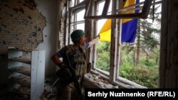 Un soldat ucrainean din Brigada 68 verifică un steag arborat pe o clădire din satul recent eliberat Blahodatne, în apropiere de linia frontului din regiunea Donețk, Ucraina, 17 iunie