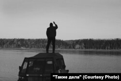 Father Mikhail tries to catch a signal with his mobile phone as he stands on the roof of his "beast-machine."