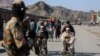 A Taliban fighter stands guard as Afghan boys help men in wheelchairs following an incident of gunfire at the Torkham border crossing between Afghanistan and Pakistan on February 20.