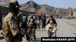 A Taliban fighter stands guard as Afghan boys help men in wheelchairs following an incident of gunfire at the Torkham border crossing between Afghanistan and Pakistan on February 20.