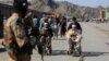 A Taliban security guard watches as young Afghan boys help elderly men in wheelchairs after gunfire between Afghanistan and Pakistan border forces near the Torkham crossing on February 20.