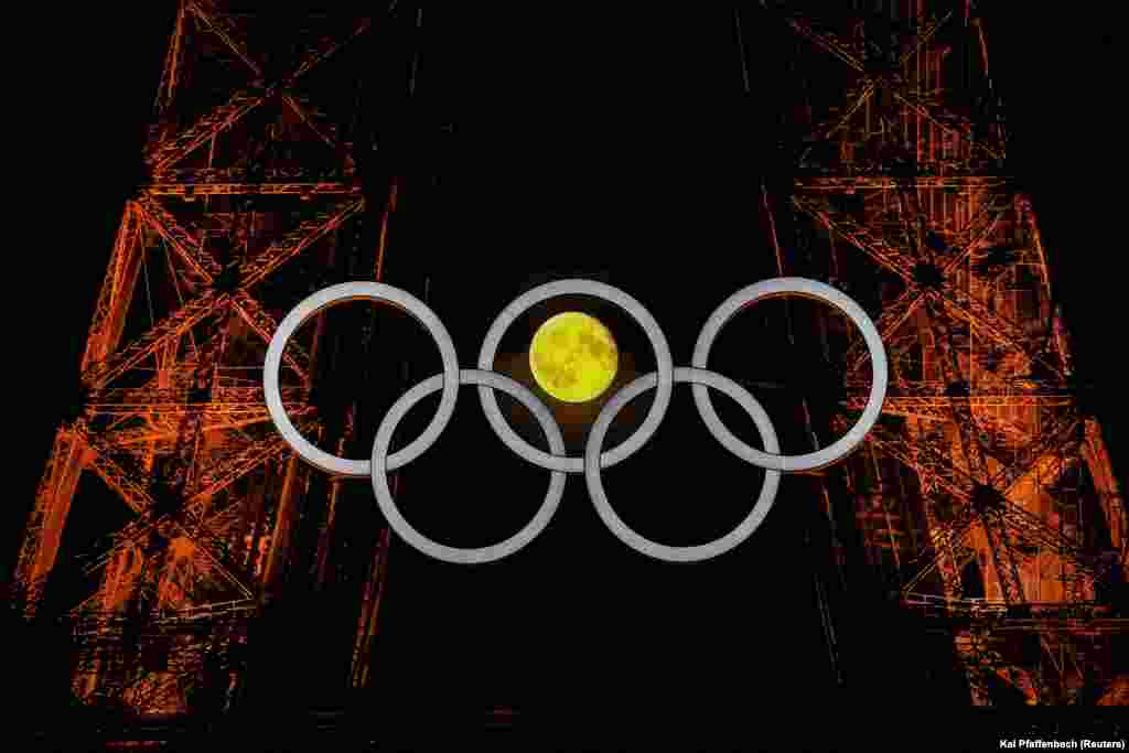 Hëna e fotografuar mes rrathëve olimpikë në Kullën Eifel, para Olimpiadës 2024 në Paris, Francë, 23 korrik 2024.