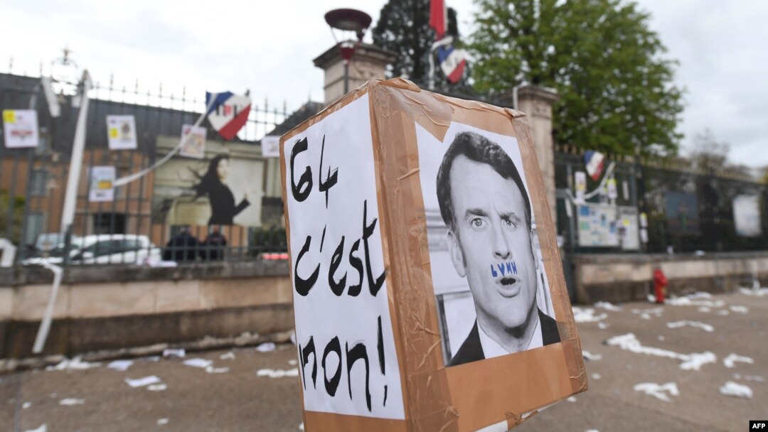 Emmanuel Macron, arătat cu o mustață formată din literele grupului de produse de lux LVMH, pe o pancartă pe care scrie „nu 64”, în fața prefecturii Sarthe, Le Mans, vestul Franței, 14 aprilie 2023.