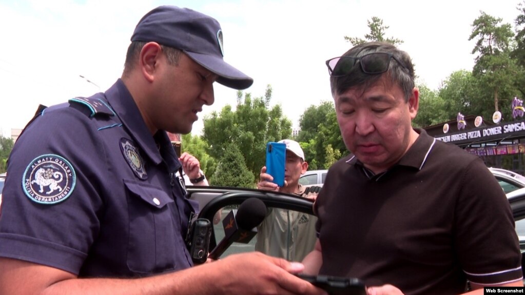 Полицейский составляет протокол на активиста Жаркыга Курентаева. 29 июня 2023 года