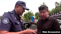 Полицейский составляет протокол на активиста Жаркына Курентаева. 29 июня 2023 года