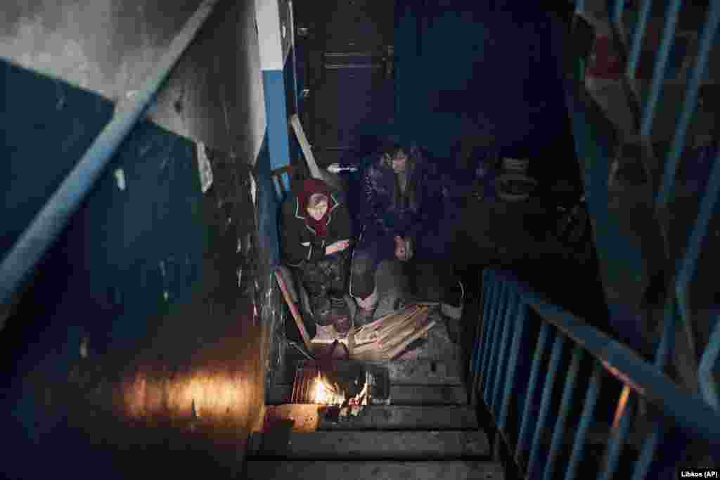 With the sounds of artillery ringing out above them, the roughly 1,500 residents who remain spend their days hiding in basements, such as these people cooking on the stairs of their apartment building on March 6.