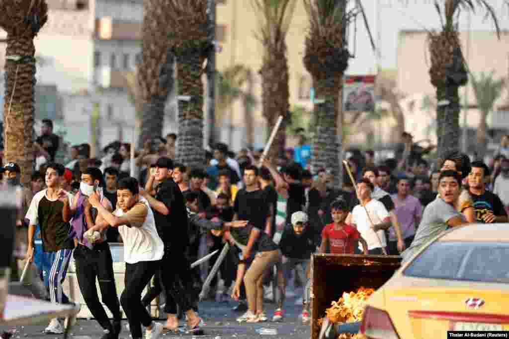 Protestuesit irakianë përgatiten të hedhin gjësende ndaj oficerëve të policisë federale ndërsa janë mbledhur për të shënuar përvjetorin e katërt të protestave antiqeveritare në Bagdad më 1 tetor.