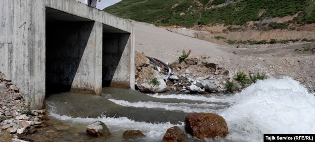 Large hoses connected to the discharge pools from the Pokrud gold mine can be seen feeding into the river, where they emit white runoff into the water. (June 2023)