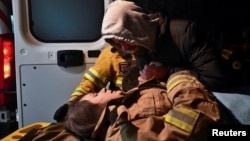 Local resident Yuriy holds the hand of his pregnant relative Anna, 27, after she was rescued from a residential building heavily damaged by a Russian missile strike in Zaporizhzhya, Ukraine, on March 2.