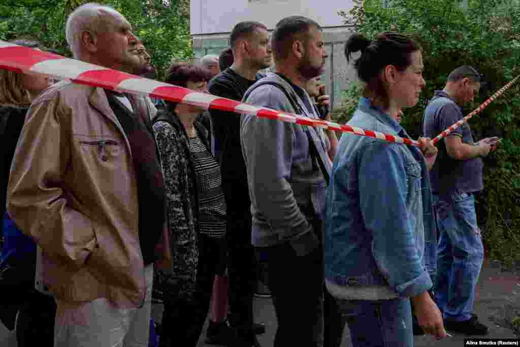 Residents watch as rescue services work at the apartment block struck by Russian missiles.