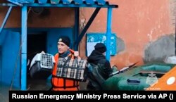 Un lucrător de urgență transportă bunurile oamenilor în timpul evacuării locuitorilor locali, după ce o parte a unui baraj s-a rupt provocând inundații, în Orsk.