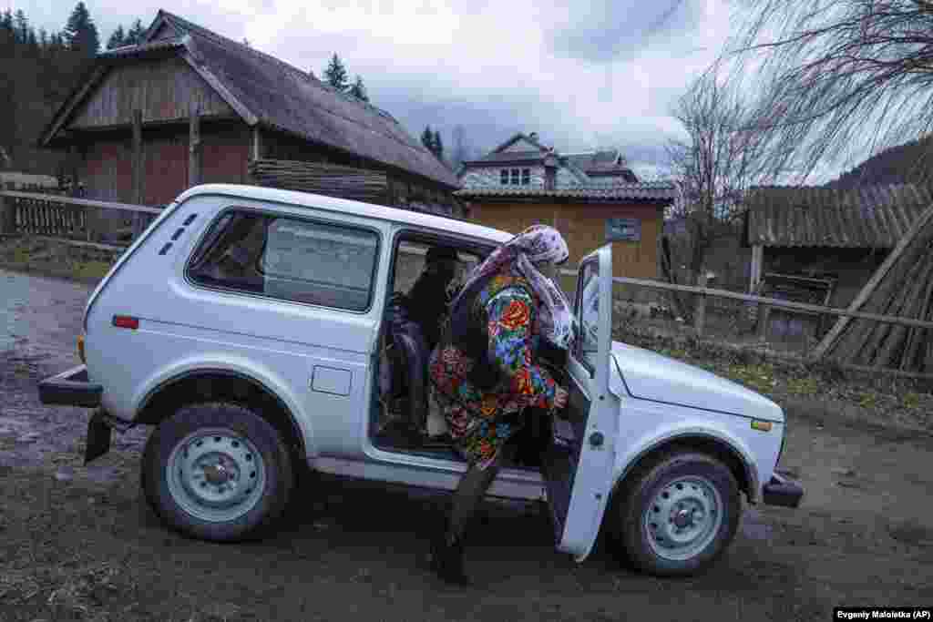 Женщина в традиционной одежде садится в машину возле церкви