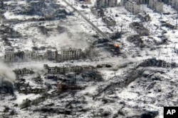 A tank (center right) fires its gun during fighting in what remains of Maryinka on February 24.