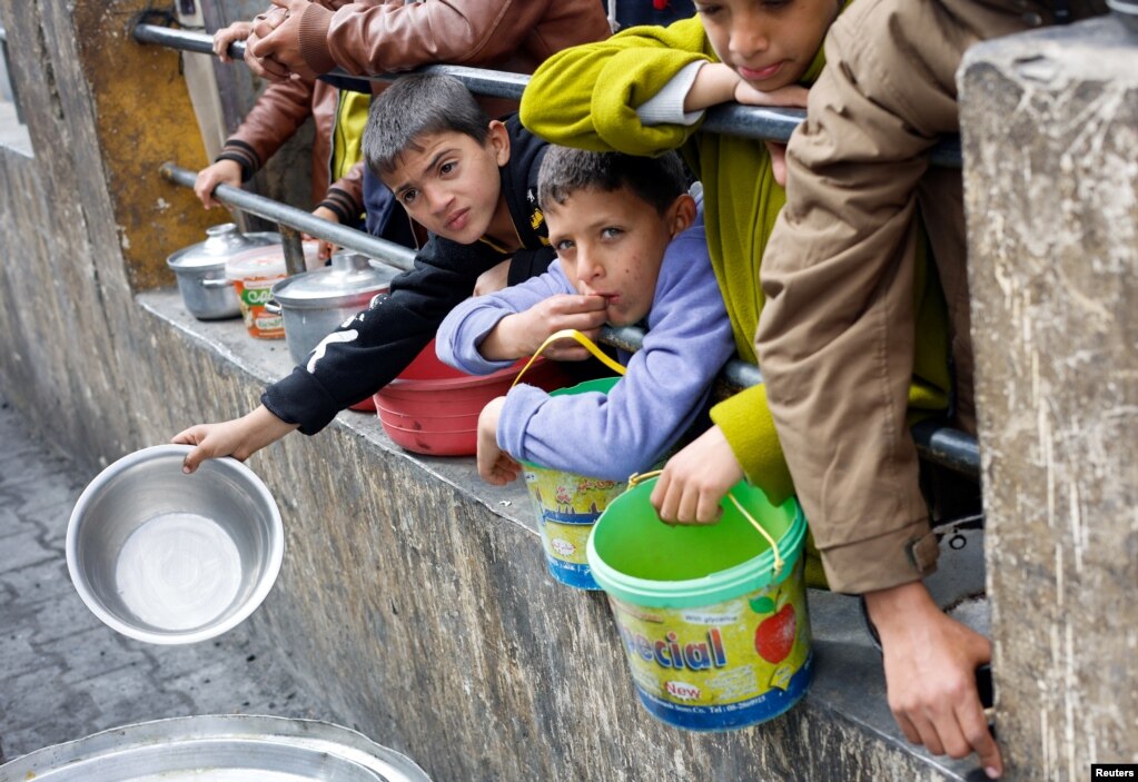 Fëmijët palestinezë presin të marrin ushqim të gatuar nga një kuzhinë bamirësie mes mungesës së madhe me furnizime ushqimore.