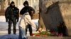 Police officers watch a woman laying flowers in tribute to Aleksei Navalny at a monument in St. Petersburg on February 18. Almost 200 people have been arrested in the city in the past week for attending memorials for the opposition activist, who died in prison on February 16. 