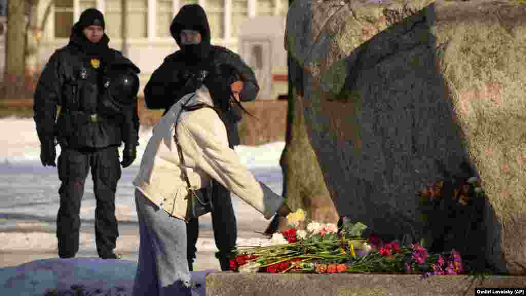 Policajci gledaju ženu kako polaže cvijeće u znak počasti ruskom opozicionom lideru Alekseju Navaljnom na spomeniku u Sankt Peterburgu 18. februara. Rusi širom zemlje su na improvizovane spomenike ostavljali cvijeće i svijeće kako bi odali počast Navaljnom, najžešćem kritičaru Kremlja . Navaljni, 47, umro je u zatvoru 16. februara pod nejasnim okolnostima. Stotine su uhapšene zbog odavanja počasti njegovoj zaostavštini.