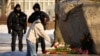 Police officers watch a woman laying flowers to pay tribute to Aleksei Navalny at a monument in St. Petersburg on February 18.